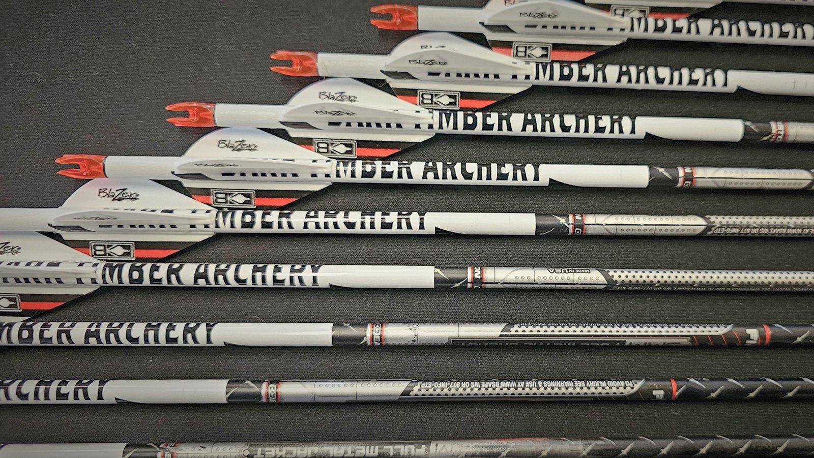 Dark Timber Archery Easton Arrows laying in a row on a black background table. 